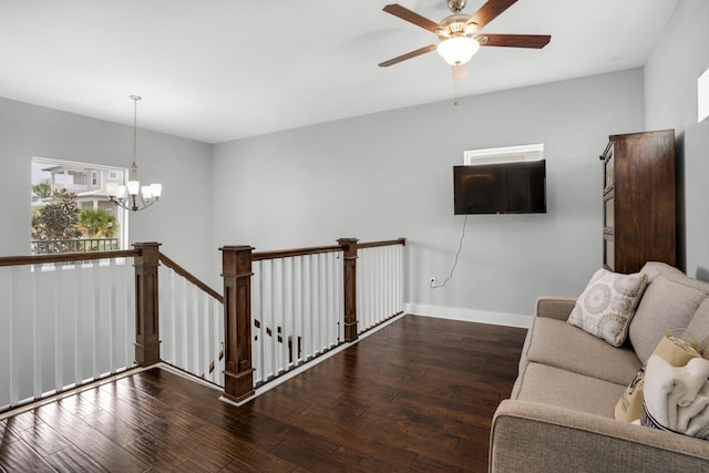 unfurnished living room featuring baseboards, wood finished floors, and ceiling fan with notable chandelier