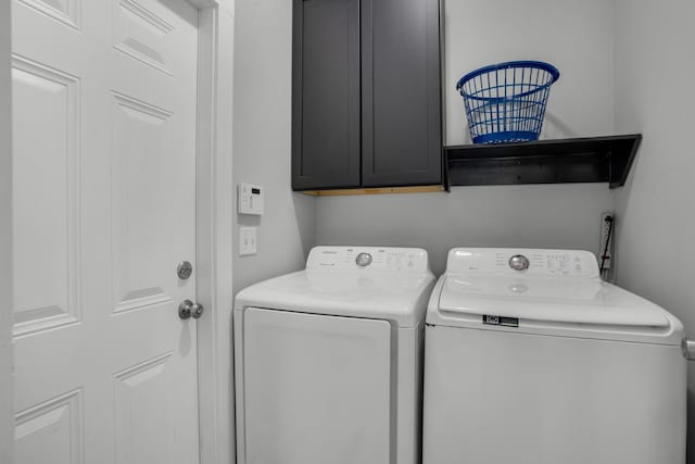 clothes washing area featuring cabinet space and washer and clothes dryer