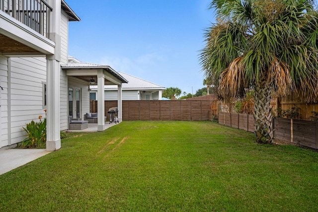 view of yard with ceiling fan, a balcony, a fenced backyard, and a patio area