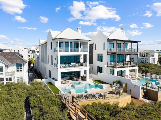 rear view of house with stucco siding, an outdoor hangout area, a chimney, a balcony, and a patio