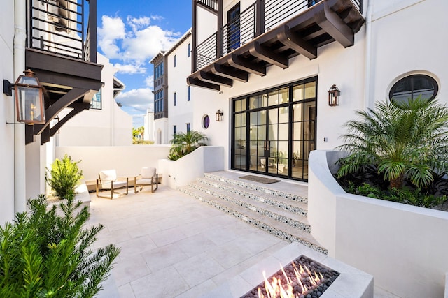 view of patio / terrace featuring french doors, a fire pit, and a balcony