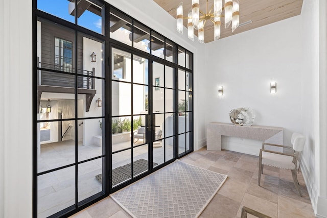 doorway to outside with a chandelier, baseboards, and a towering ceiling