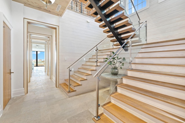 staircase with wooden walls and a towering ceiling