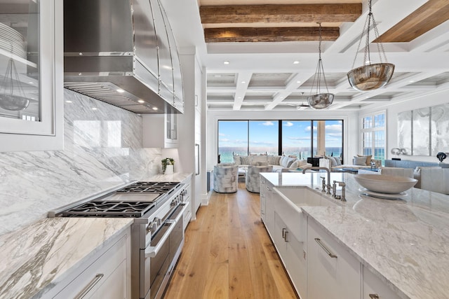 kitchen with beam ceiling, tasteful backsplash, open floor plan, white cabinetry, and stainless steel stove