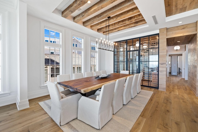 dining room featuring beamed ceiling, baseboards, a chandelier, and light wood finished floors