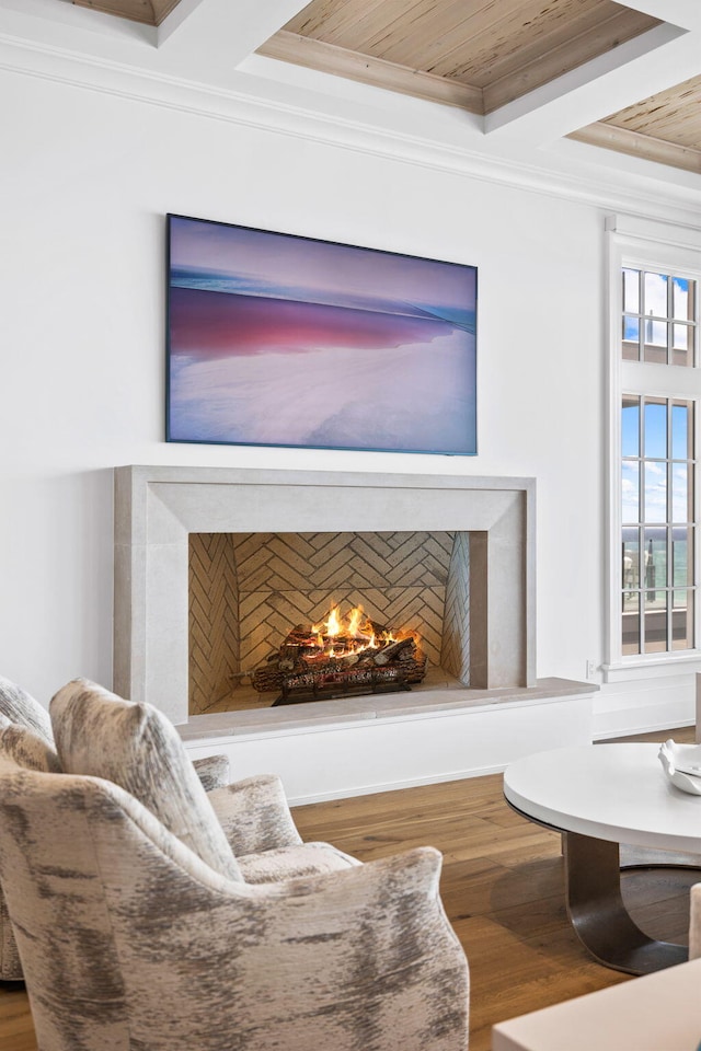 sitting room with a premium fireplace, wood ceiling, wood finished floors, and ornamental molding