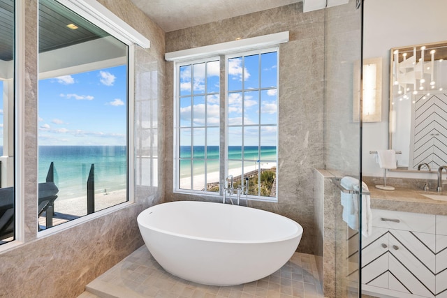 full bathroom with a water view, a freestanding bath, and vanity