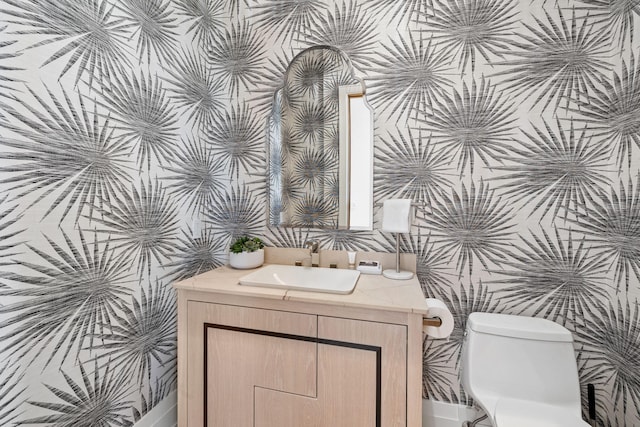 bathroom featuring toilet, wallpapered walls, and vanity