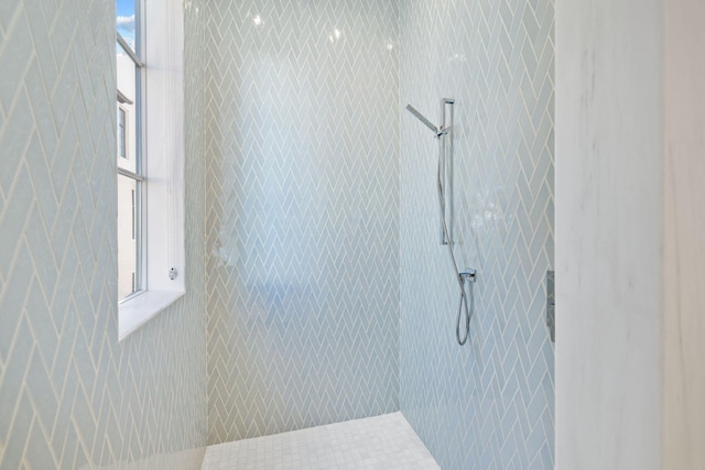 full bathroom with a tile shower and plenty of natural light