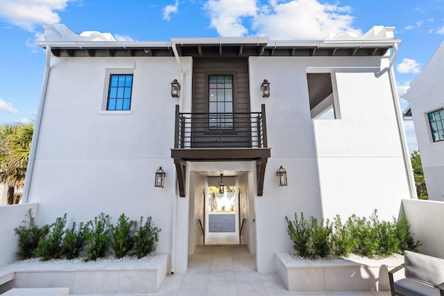 view of front of house featuring stucco siding, concrete driveway, and a balcony