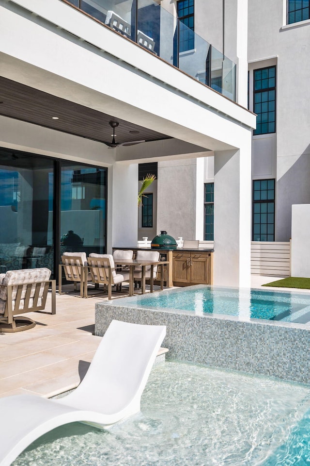 view of pool with grilling area, ceiling fan, exterior kitchen, a patio area, and an infinity pool