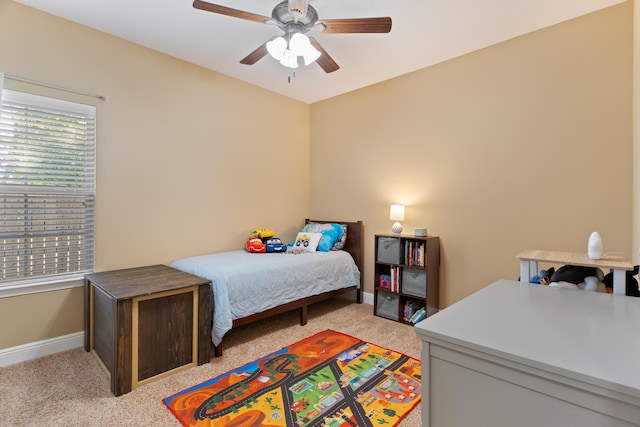 bedroom featuring light carpet, a ceiling fan, and baseboards