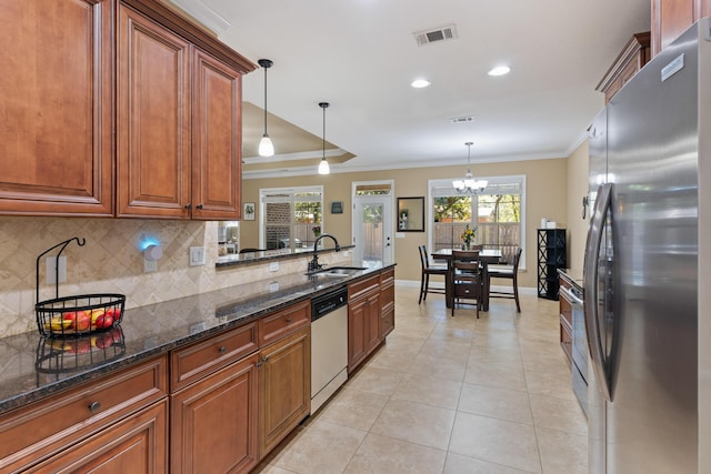 kitchen featuring visible vents, a sink, backsplash, stainless steel appliances, and crown molding