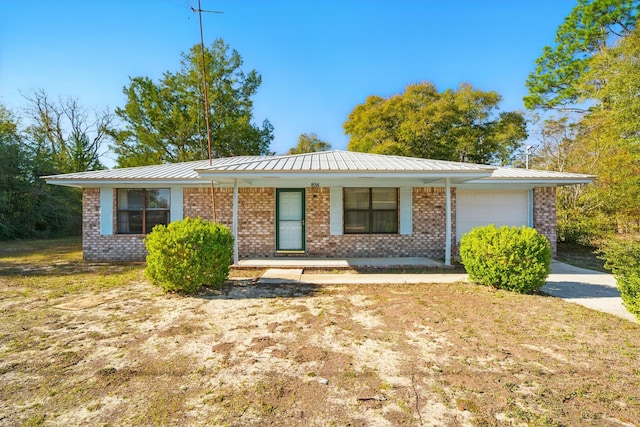 ranch-style home featuring brick siding, covered porch, an attached garage, and metal roof