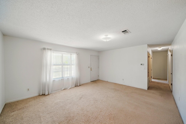 unfurnished room with visible vents, light carpet, and a textured ceiling