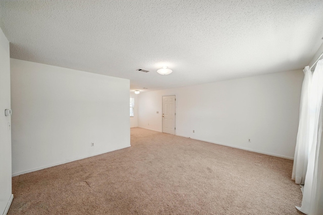 carpeted spare room featuring visible vents, baseboards, and a textured ceiling