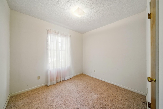 carpeted spare room featuring baseboards and a textured ceiling