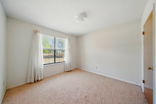 carpeted empty room featuring a textured ceiling and baseboards