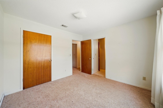 unfurnished bedroom featuring visible vents, baseboards, a closet, and light carpet