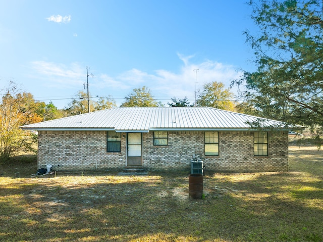 rear view of house featuring metal roof, a lawn, and brick siding