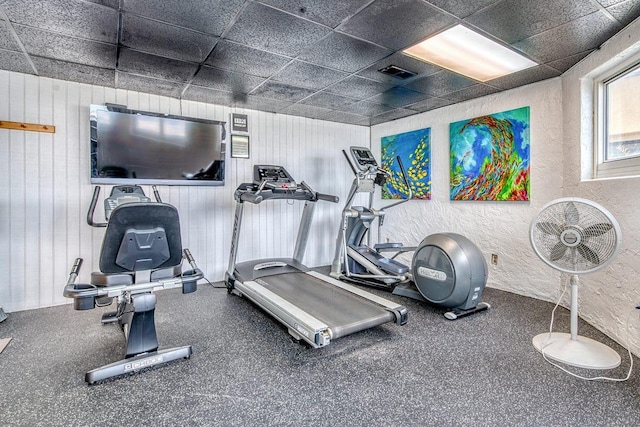 workout room with visible vents, a paneled ceiling, and a textured wall