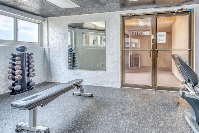 exercise room with a paneled ceiling and a textured wall