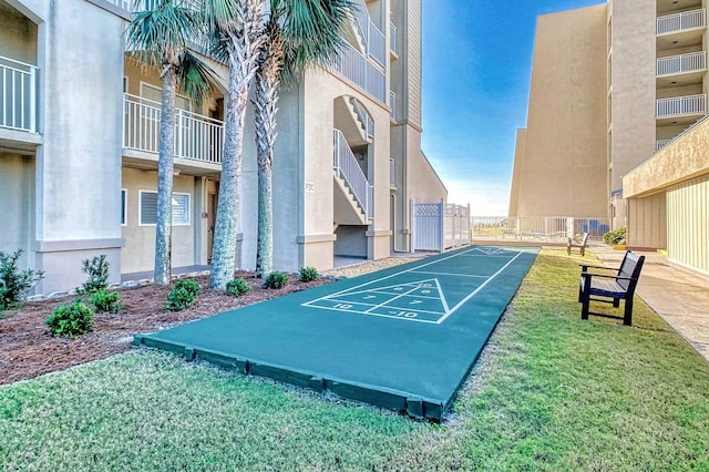 view of property's community with shuffleboard and a yard