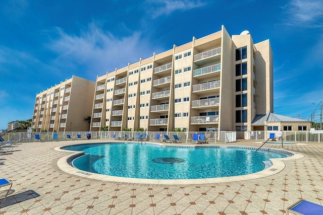 community pool with a patio and fence