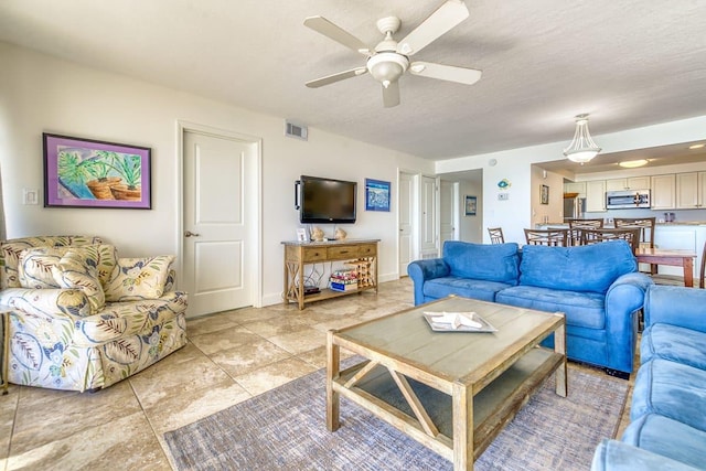 living area featuring visible vents, a textured ceiling, and ceiling fan