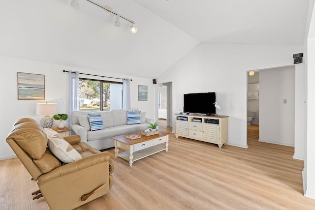 living room featuring baseboards, light wood-style flooring, track lighting, and vaulted ceiling