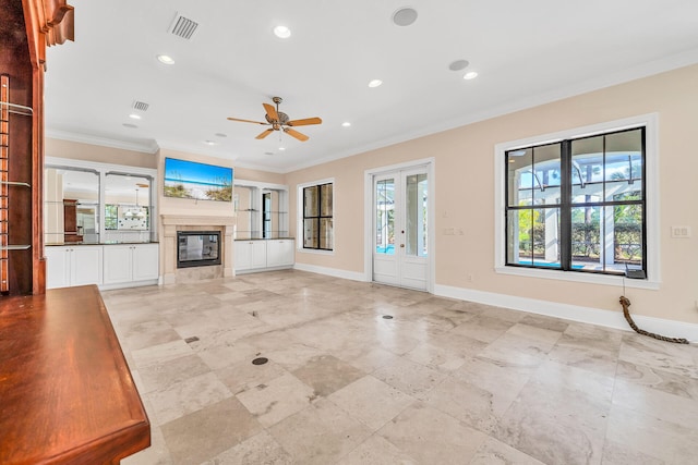 unfurnished living room with crown molding, baseboards, a wealth of natural light, and a tile fireplace