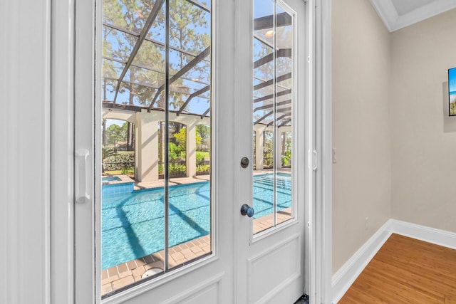 doorway to outside featuring wood finished floors, baseboards, and ornamental molding