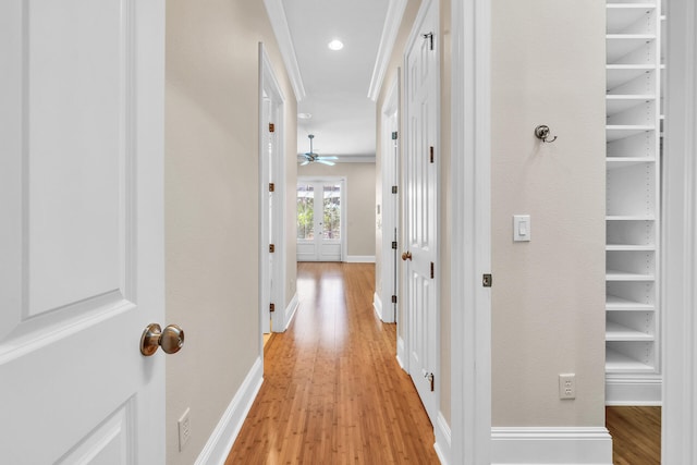 corridor with recessed lighting, light wood-style flooring, baseboards, and ornamental molding