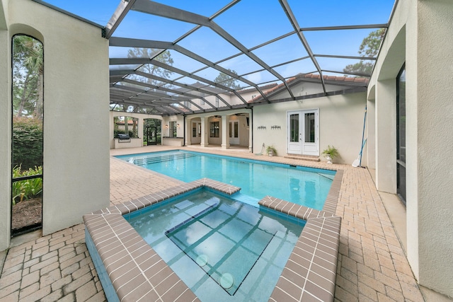 view of swimming pool featuring a patio area, glass enclosure, french doors, and a pool with connected hot tub