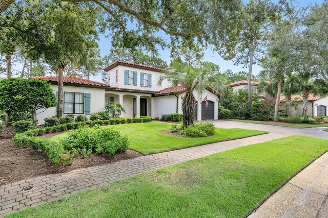 mediterranean / spanish-style house featuring a front yard, driveway, stucco siding, a garage, and a tile roof