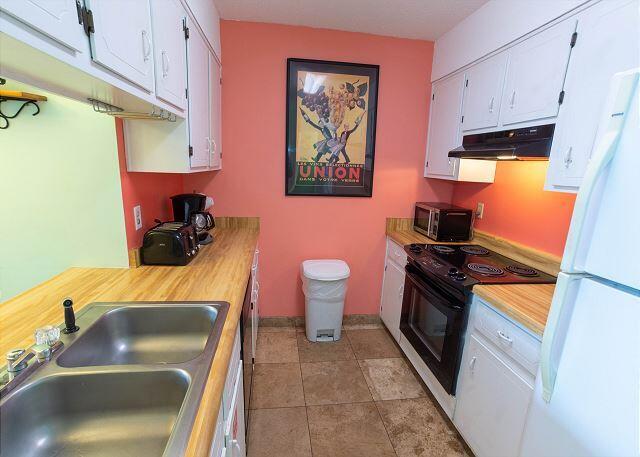 kitchen featuring black electric range oven, under cabinet range hood, stainless steel microwave, a sink, and freestanding refrigerator