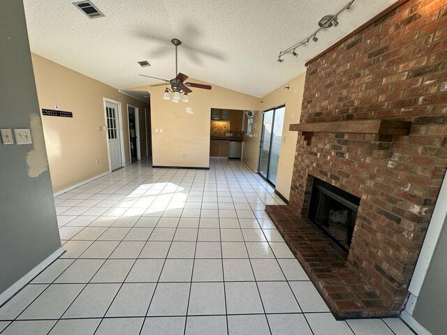 unfurnished living room with light tile patterned floors, visible vents, lofted ceiling, a textured ceiling, and a brick fireplace