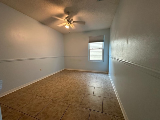 tiled spare room with a textured ceiling, baseboards, and ceiling fan