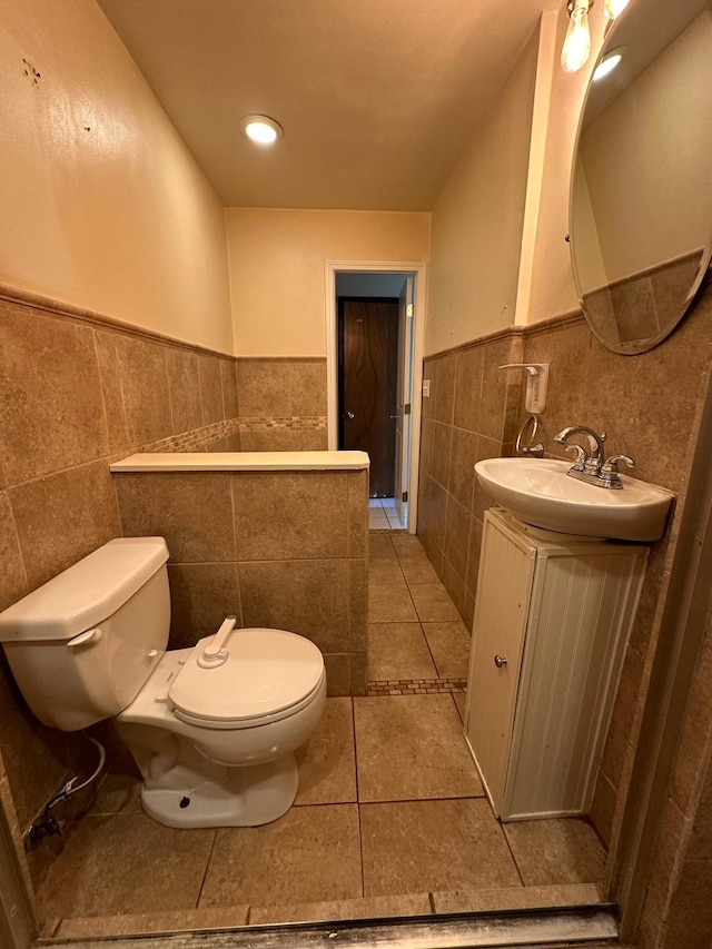 bathroom with vanity, a wainscoted wall, tile patterned flooring, tile walls, and toilet