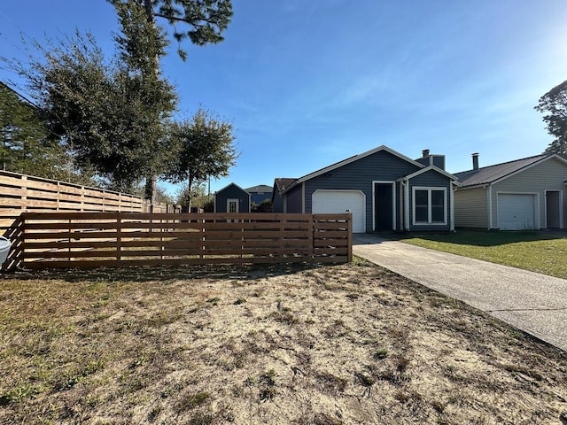 view of yard with concrete driveway, a garage, and fence