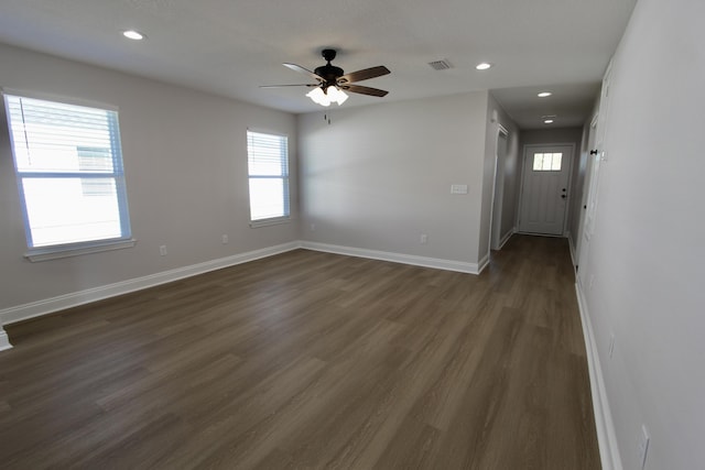 empty room featuring visible vents, recessed lighting, baseboards, ceiling fan, and dark wood-style flooring