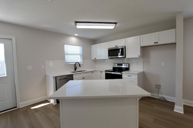 kitchen featuring baseboards, dark wood-style flooring, a sink, stainless steel appliances, and backsplash