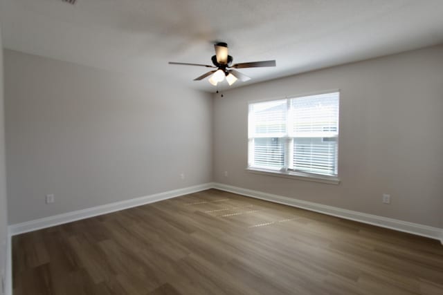 spare room with dark wood-type flooring, baseboards, and ceiling fan