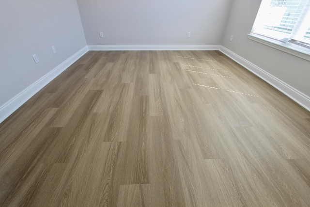 spare room featuring baseboards and wood finished floors