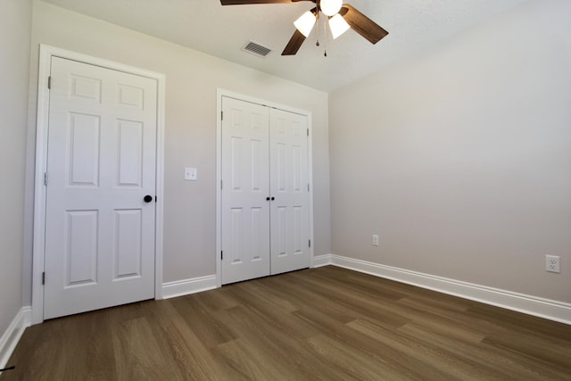 unfurnished bedroom featuring visible vents, dark wood finished floors, a closet, baseboards, and ceiling fan