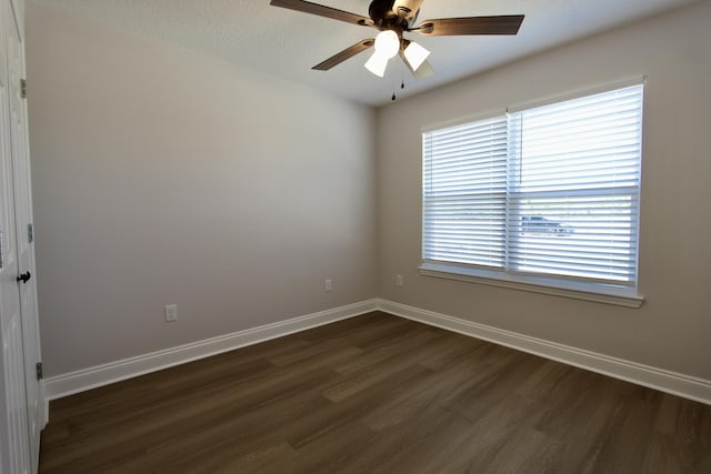 spare room featuring baseboards, dark wood-type flooring, and ceiling fan