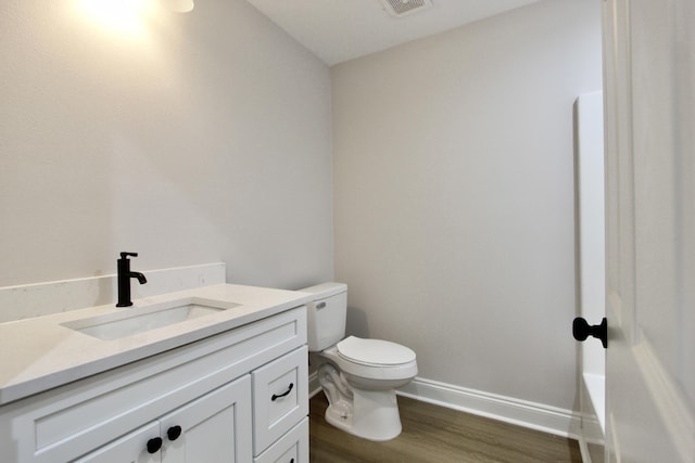 bathroom featuring vanity, toilet, wood finished floors, and baseboards