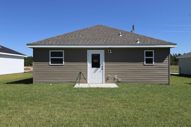 back of property with a yard and a shingled roof