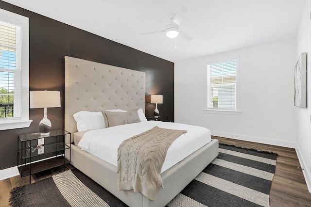 bedroom with a ceiling fan, multiple windows, wood finished floors, and baseboards