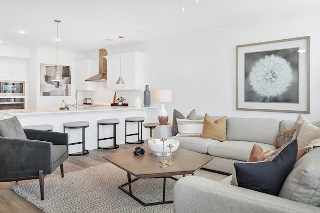 living area with recessed lighting, light wood-style flooring, and ornamental molding